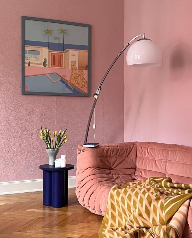 Pink painted living room wall with pink sofa and contrasting furniture