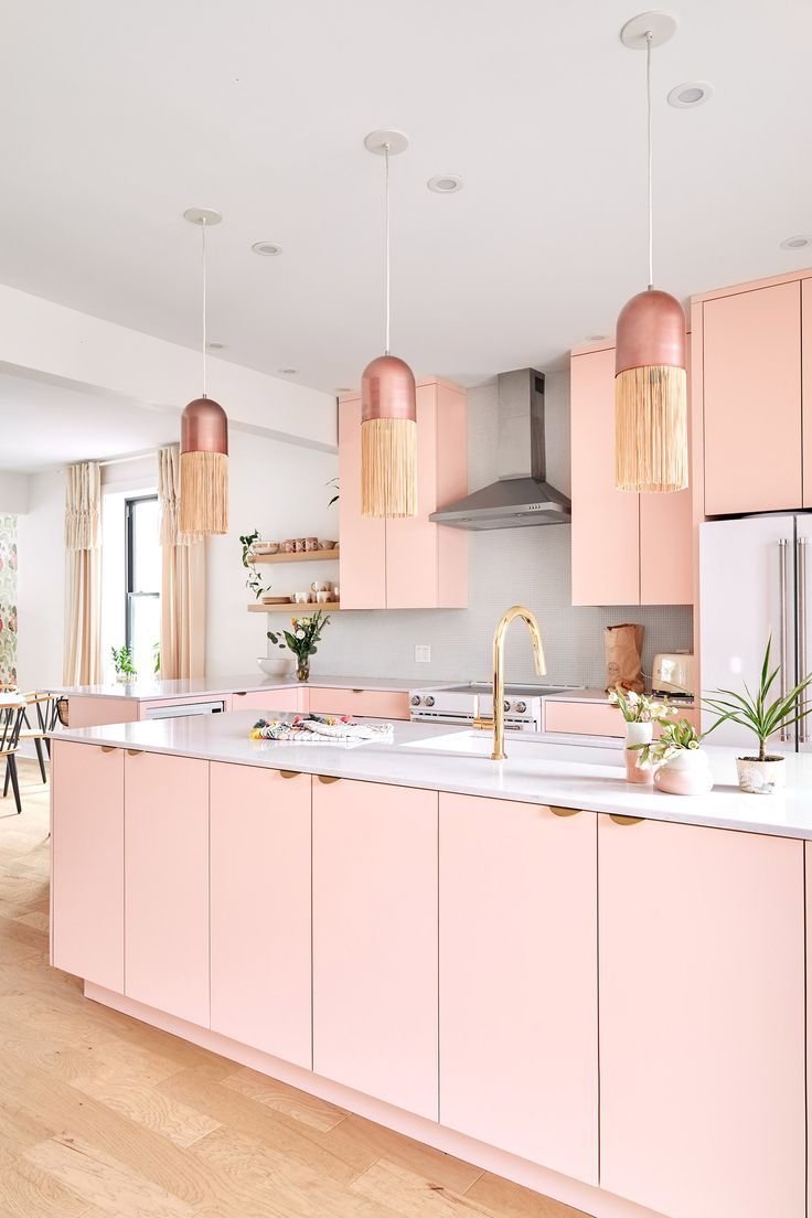 Elegant pale pink kitchen cabinets with white countertops and brass accents