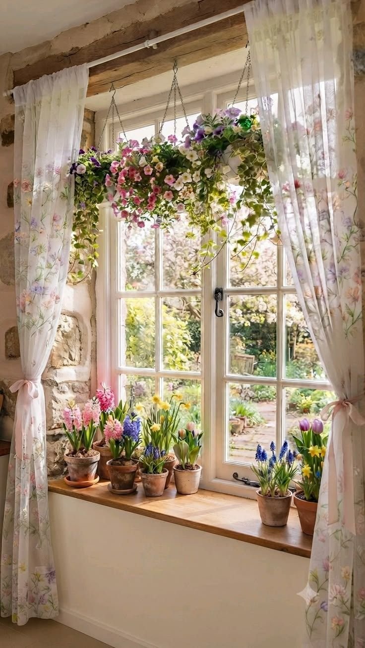 Cottage window with terracotta pots of spring flowers on the sill, floral curtains and a hanging flower basket