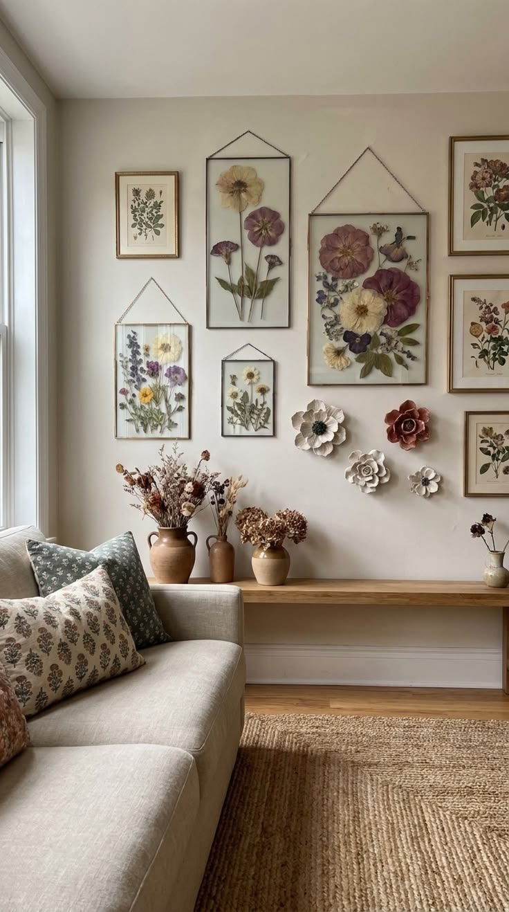 Gallery wall of pressed flower frames and botanical prints above a wooden bench with terracotta vases