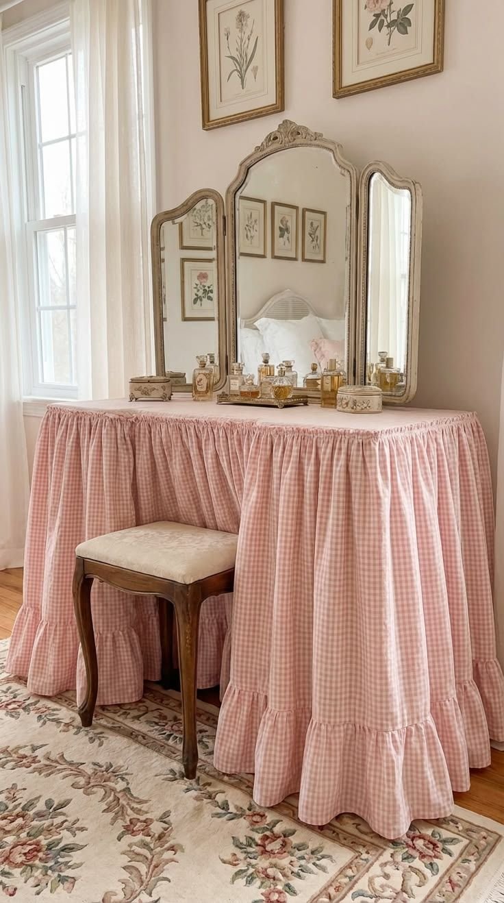 Pink gingham skirted vanity table with a ruffled hem, antique mirror and botanical prints above