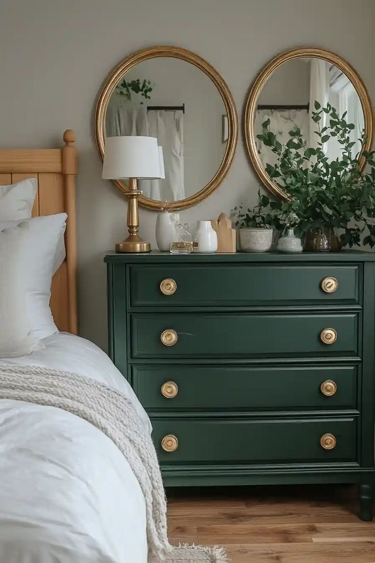 Deep green painted dresser with brass knobs and two gold framed round mirrors above
