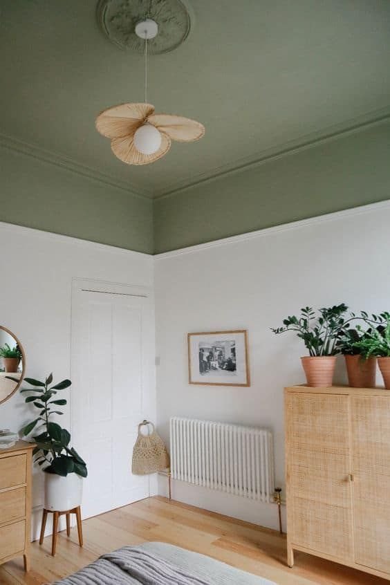 Sage green painted bedroom ceiling above white walls with a rattan pendant light