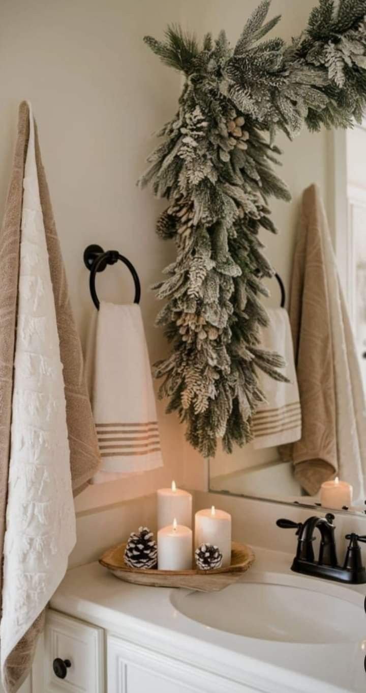 Snow-flocked Christmas garland draped over a bathroom mirror with lit candles