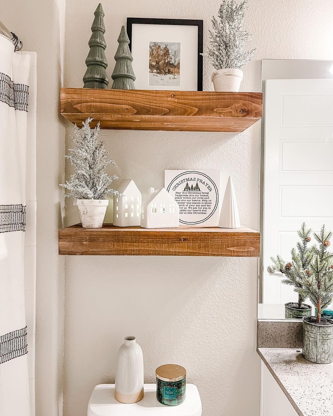 Two-shelf bathroom display with framed watercolor art and bottle brush Christmas trees