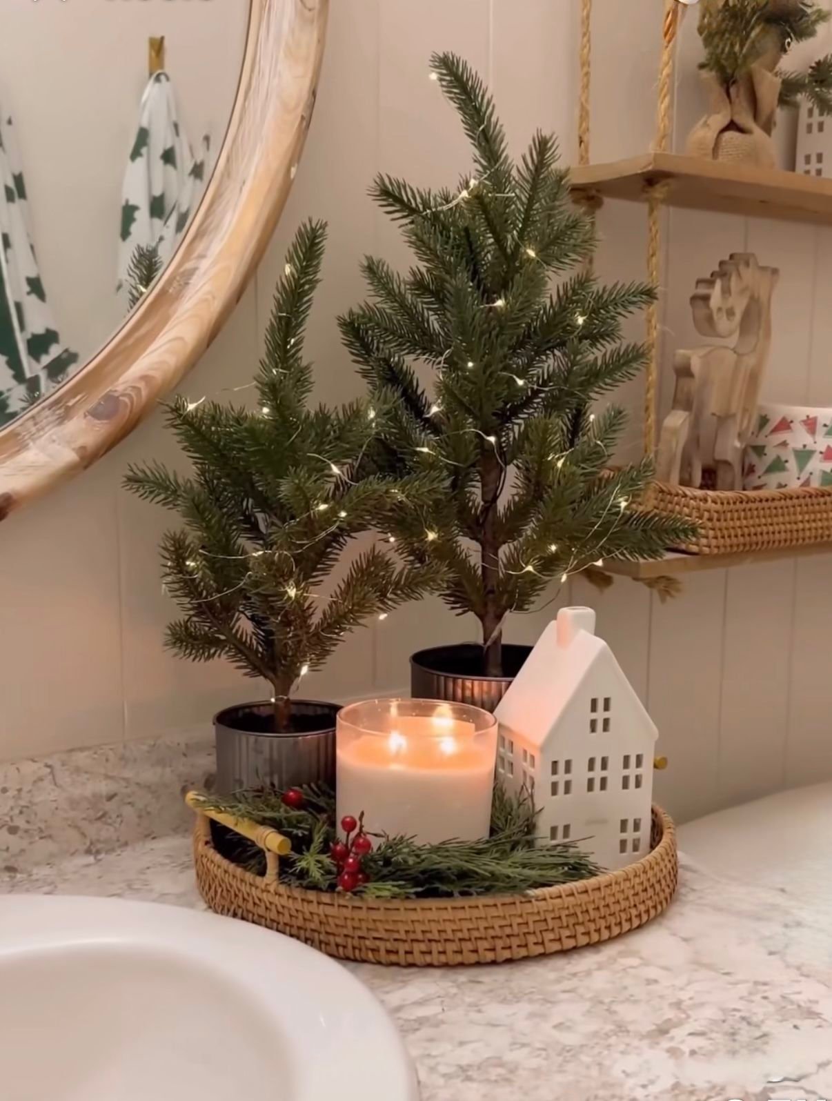 Candlelit wooden tray with mini Christmas trees and a small lit house