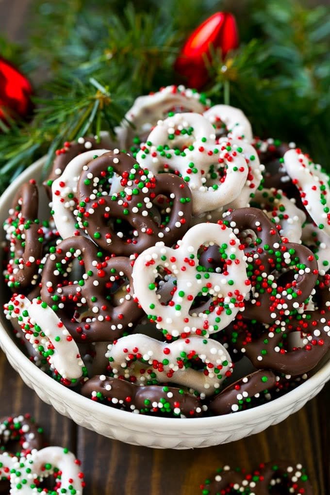A bowl of chocolate covered pretzels topped with red, green, and white sprinkles