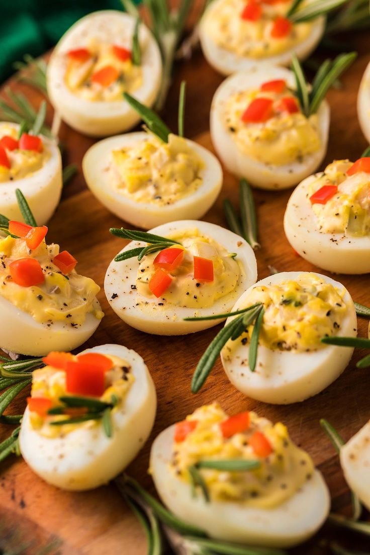 Deviled eggs garnished with diced red pepper and rosemary