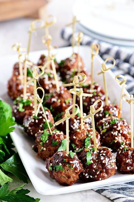 Glazed mini meatballs with sesame seeds on decorative picks