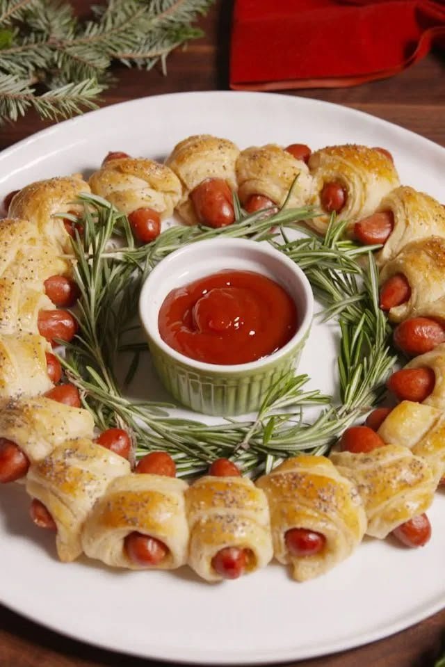 Pigs in blankets arranged in a wreath shape with a bowl of ketchup