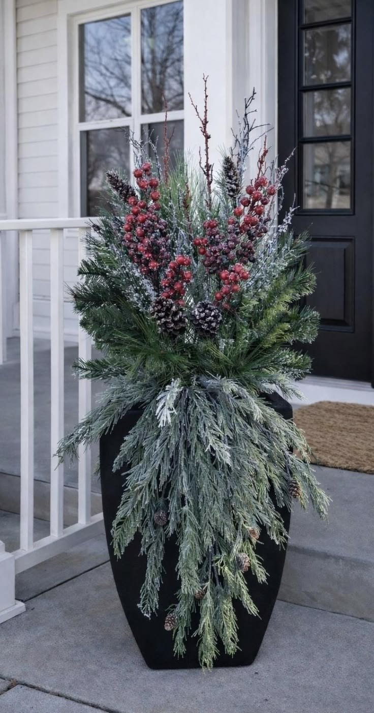 Tall black urn with frosted evergreen branches and dark red berries