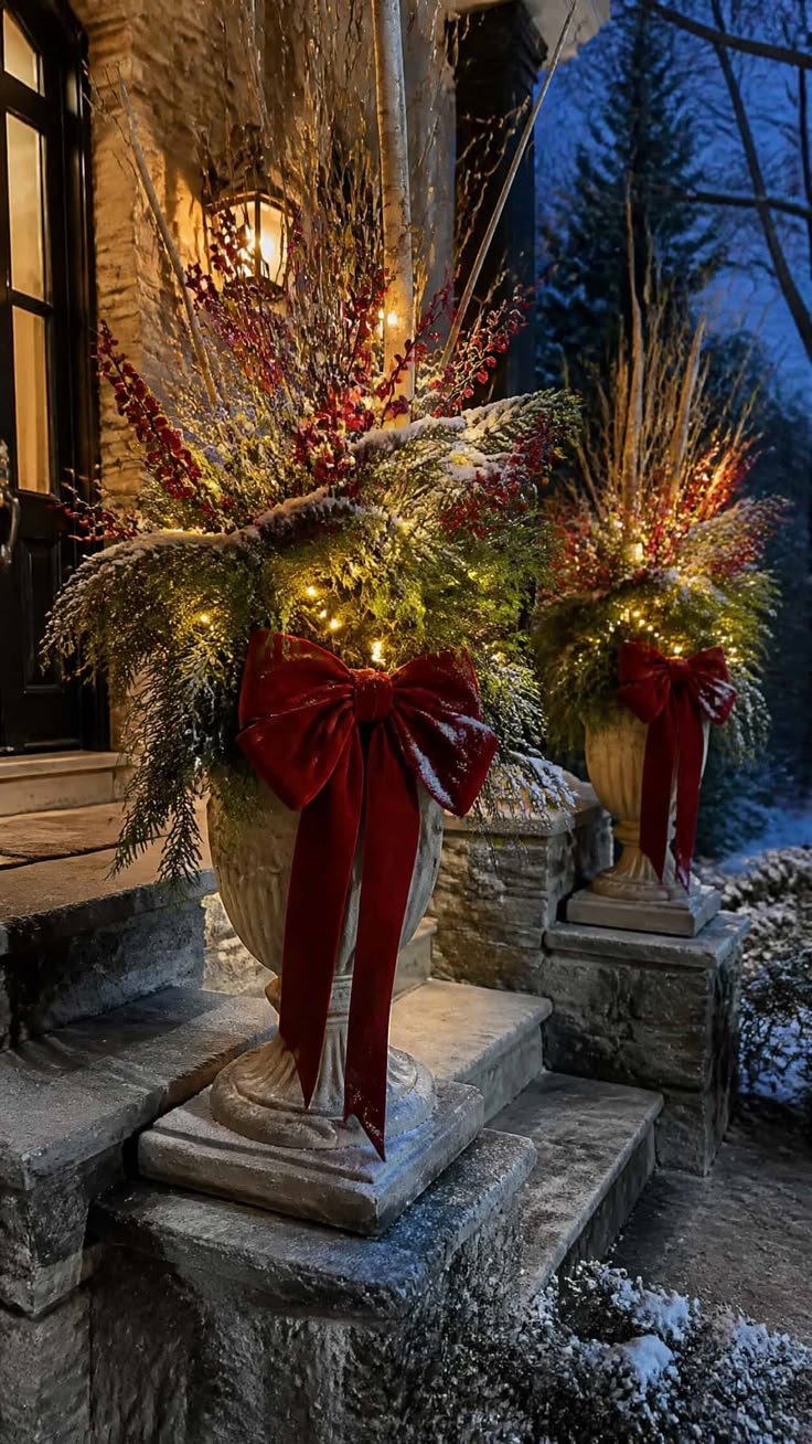 Stone urns on porch steps with oversized red velvet bows and fairy lights