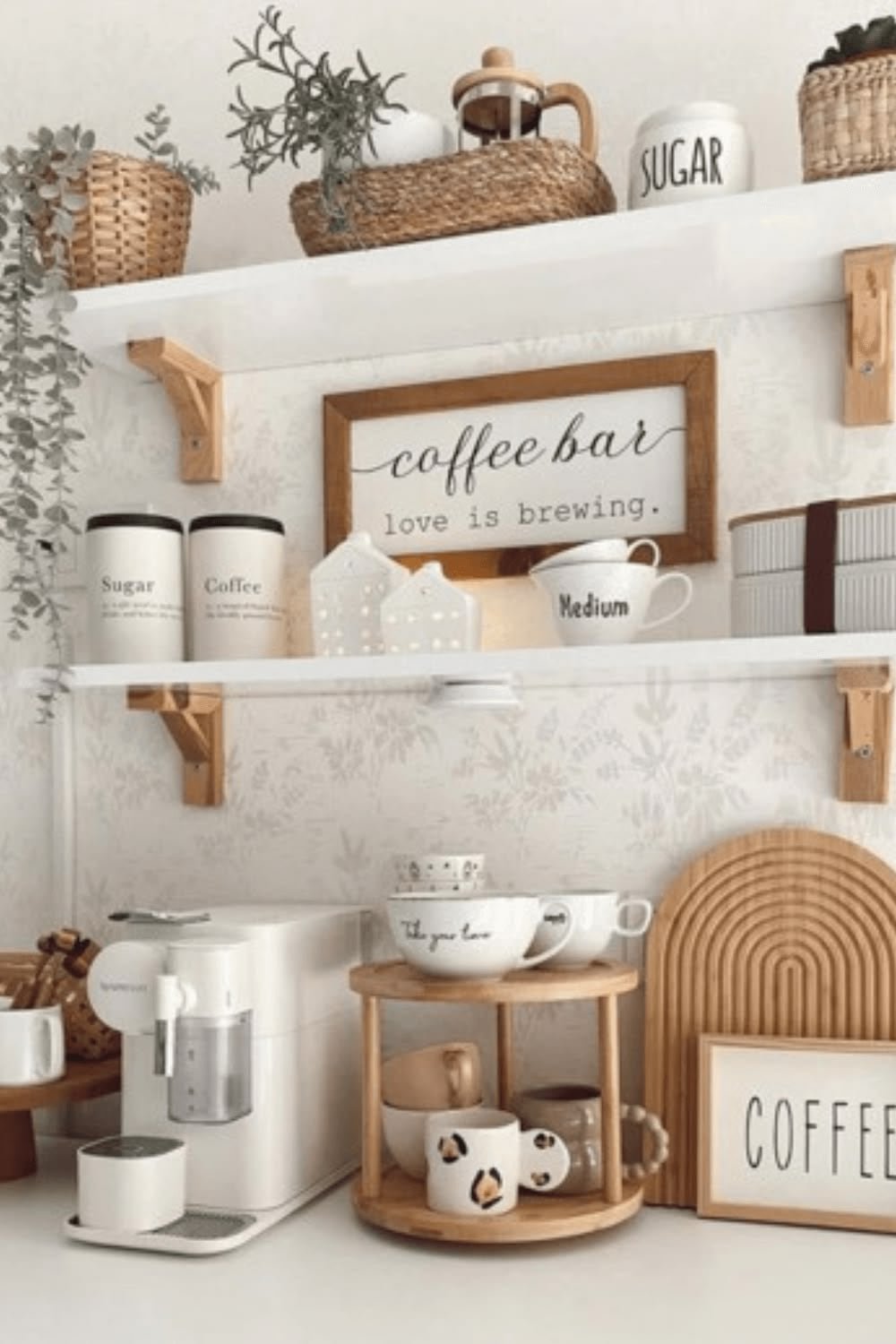 White shelves on wood brackets with a coffee bar sign, woven baskets and canisters above a white coffee machine