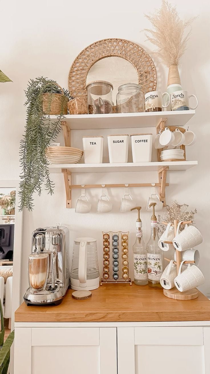 White shelves with white mugs hanging from hooks underneath and a wooden mug tree beside an espresso machine