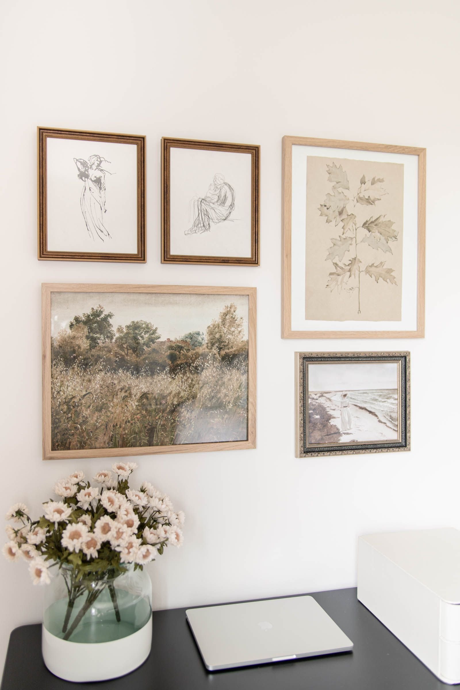 Vintage gallery wall with mismatched frames above a small desk nook in a cottagecore bedroom