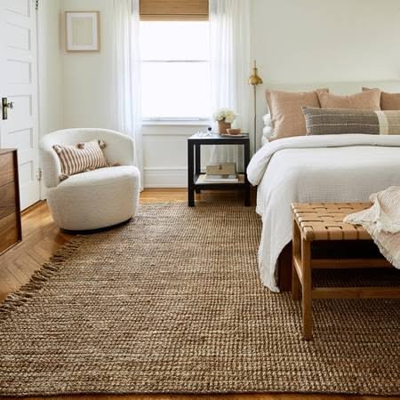 Cozy cottagecore reading nook with a boucle chair and a natural jute rug
