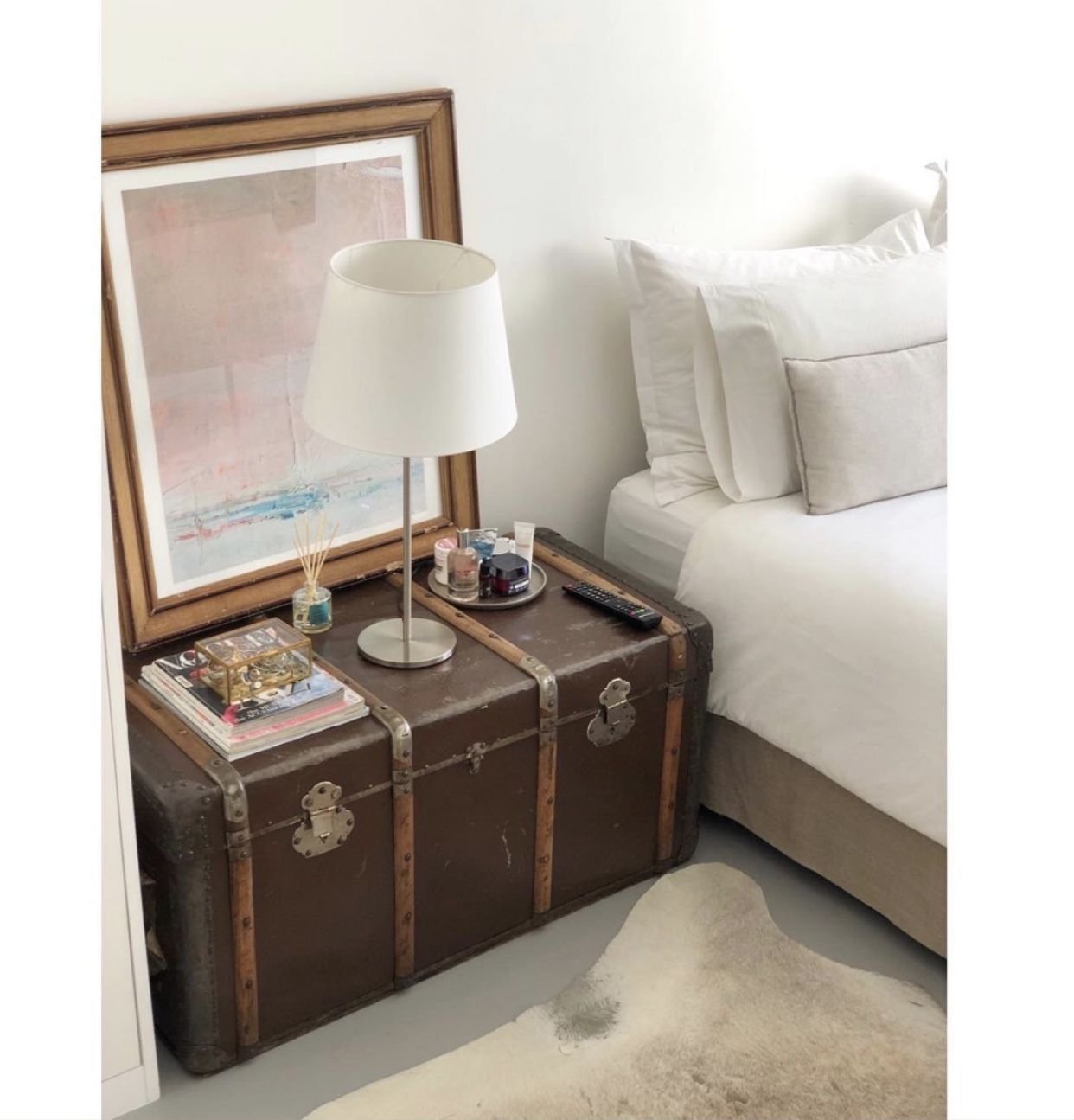 Vintage trunk used as a nightstand beside a lamp in a cottagecore bedroom