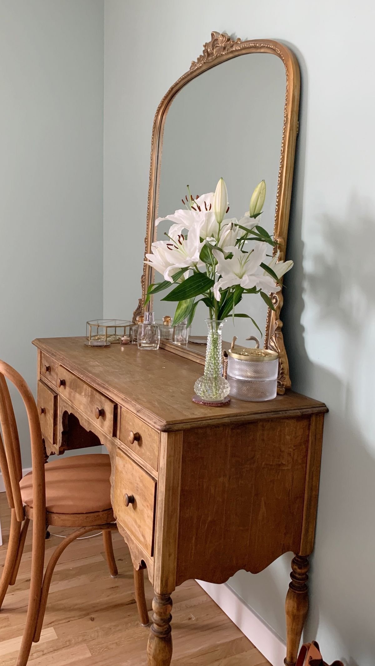 Vintage vanity desk with a gilded arched mirror in a cottagecore bedroom