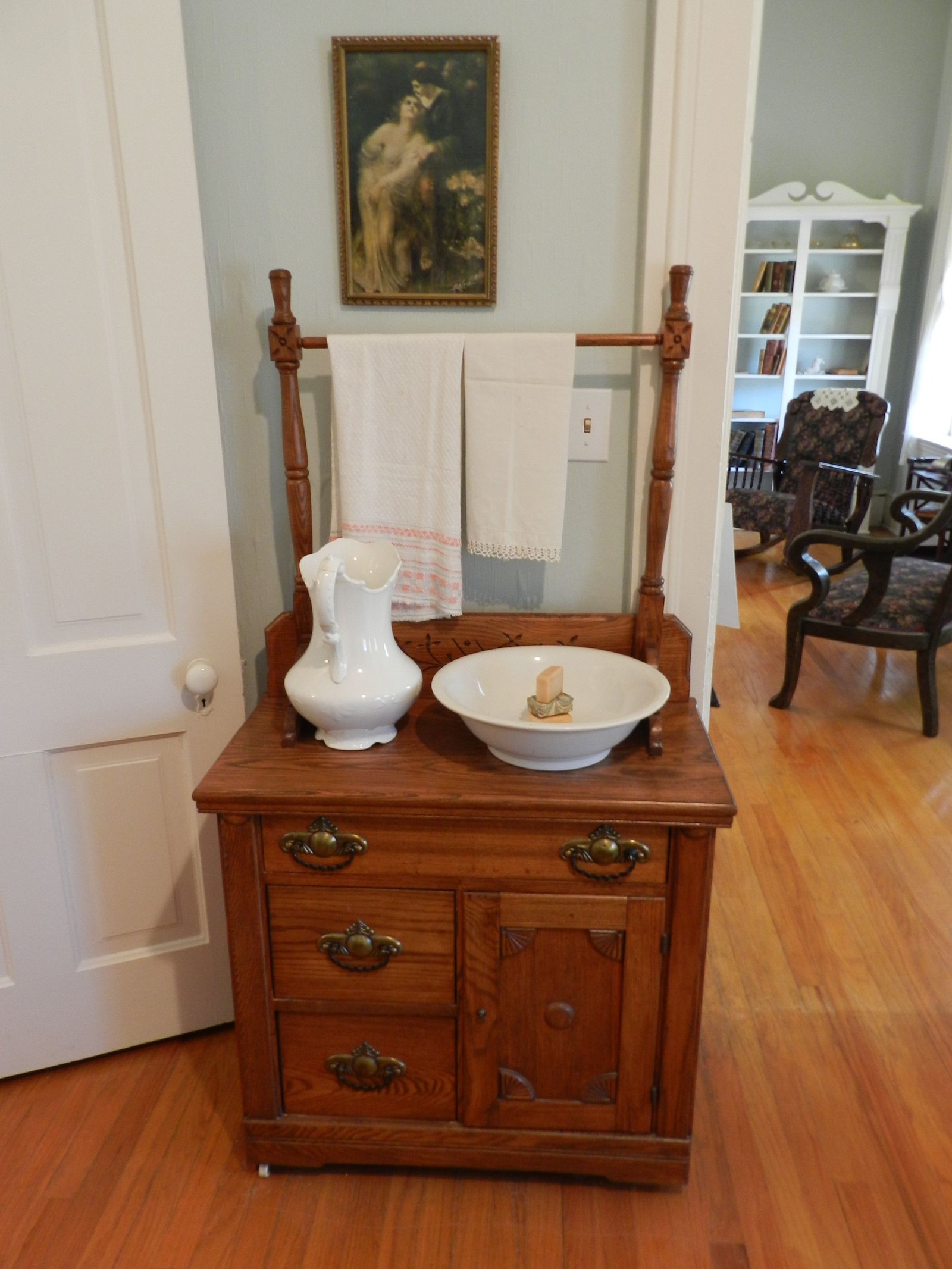 Antique washstand with a ceramic pitcher and bowl styled as cottagecore bedroom decor