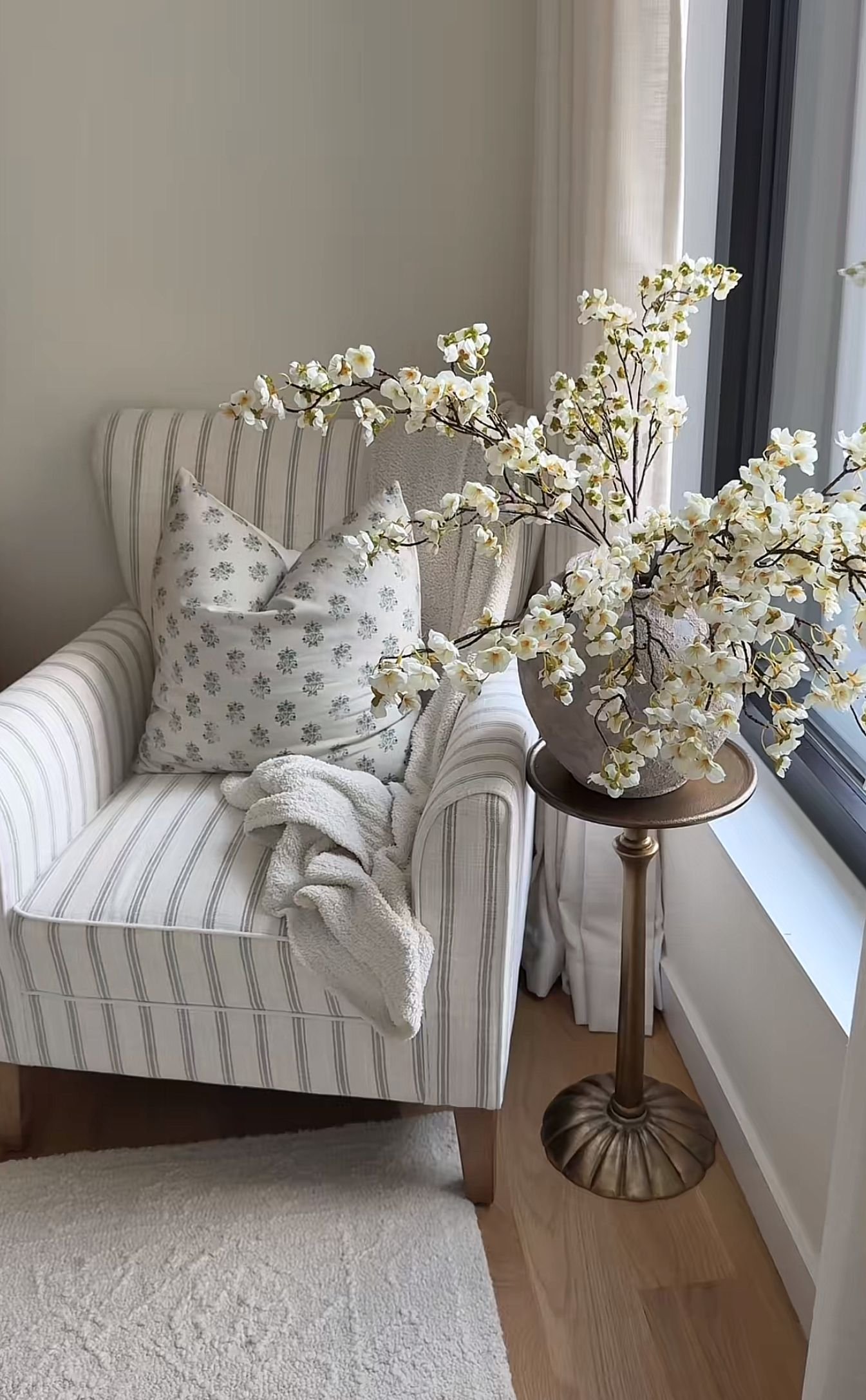Floral upholstered armchair positioned in front of a curtained window