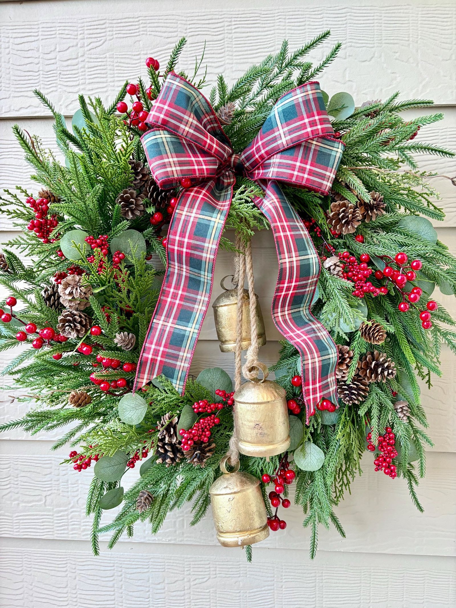 Pine wreath with gold bells and a red plaid ribbon bow