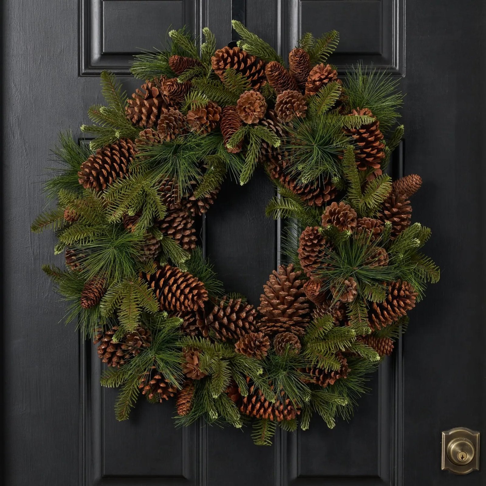 Natural pinecone and pine wreath with no ribbon on a black door