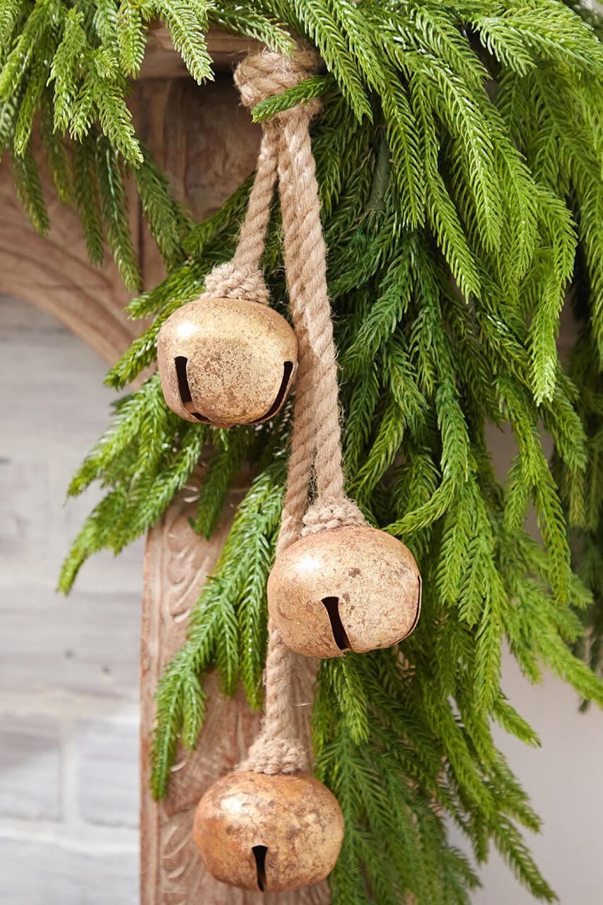 Close-up of rustic jingle bells tied with jute rope hanging from pine garland