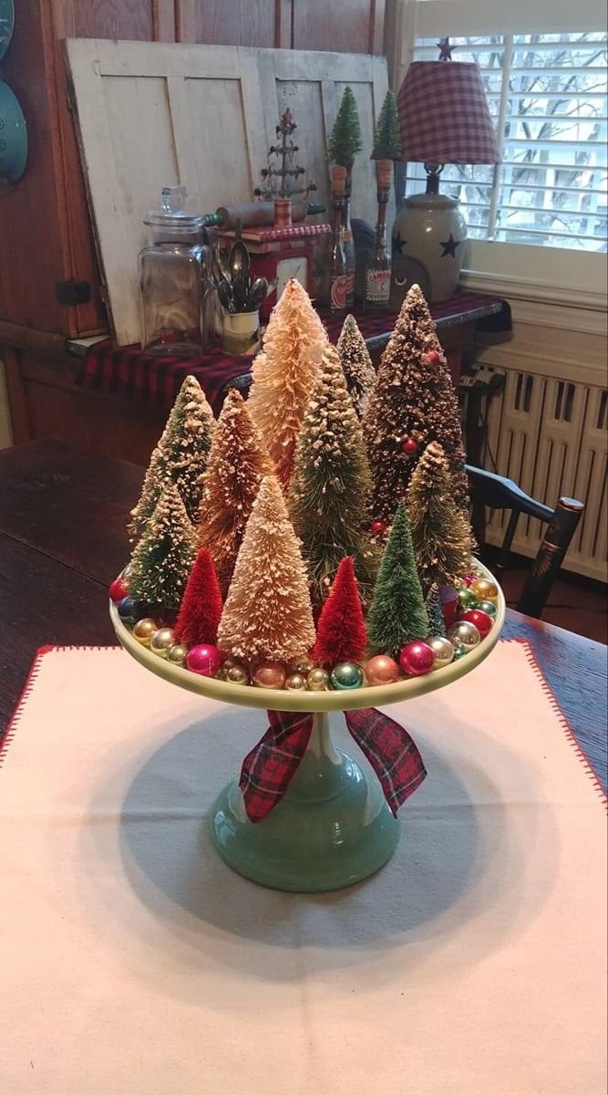 Bottle brush Christmas trees and vintage ornaments displayed on a green cake stand