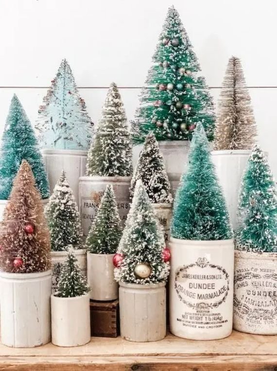 Bottle brush Christmas trees in vintage ceramic crocks on a wooden table