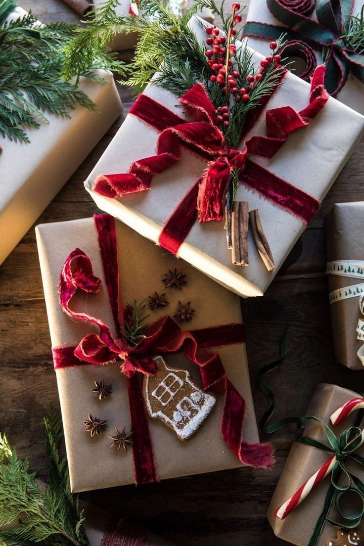 Gifts wrapped in kraft paper with burgundy velvet ribbon bows and greenery