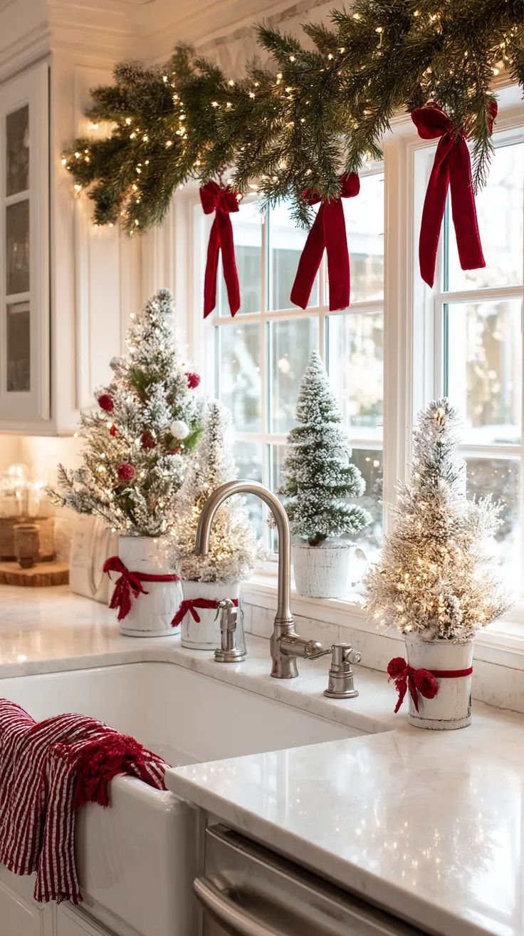 Flocked mini Christmas trees lined up along a farmhouse kitchen sink window