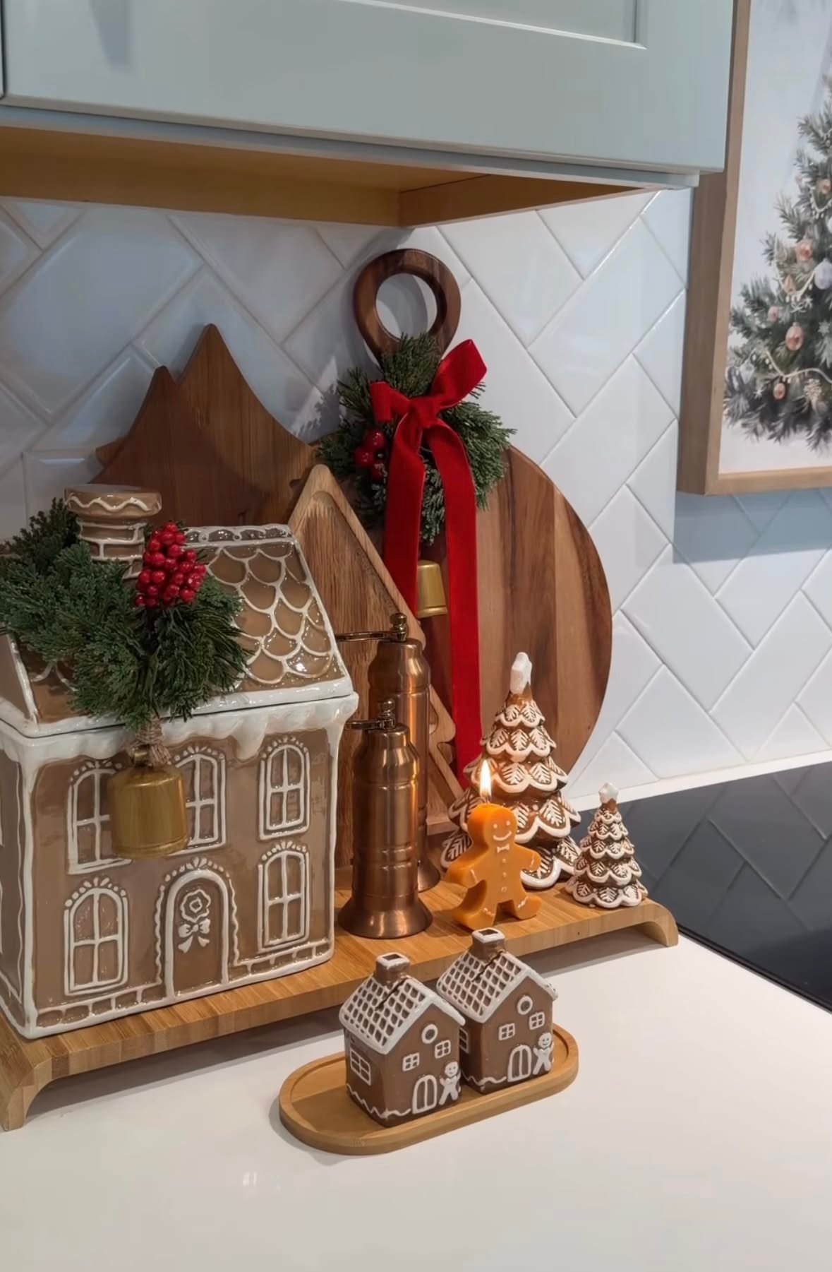 A gingerbread house cookie jar styled on a wood cutting board with candles