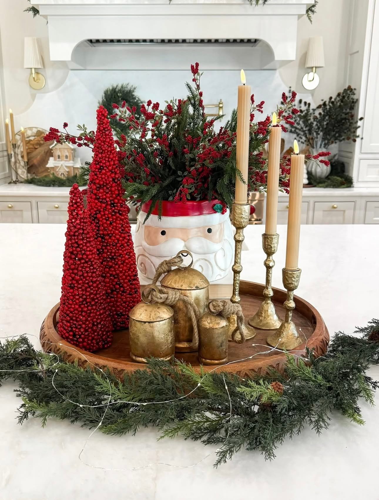 A Santa mug used as a vase with brass bells on a kitchen counter