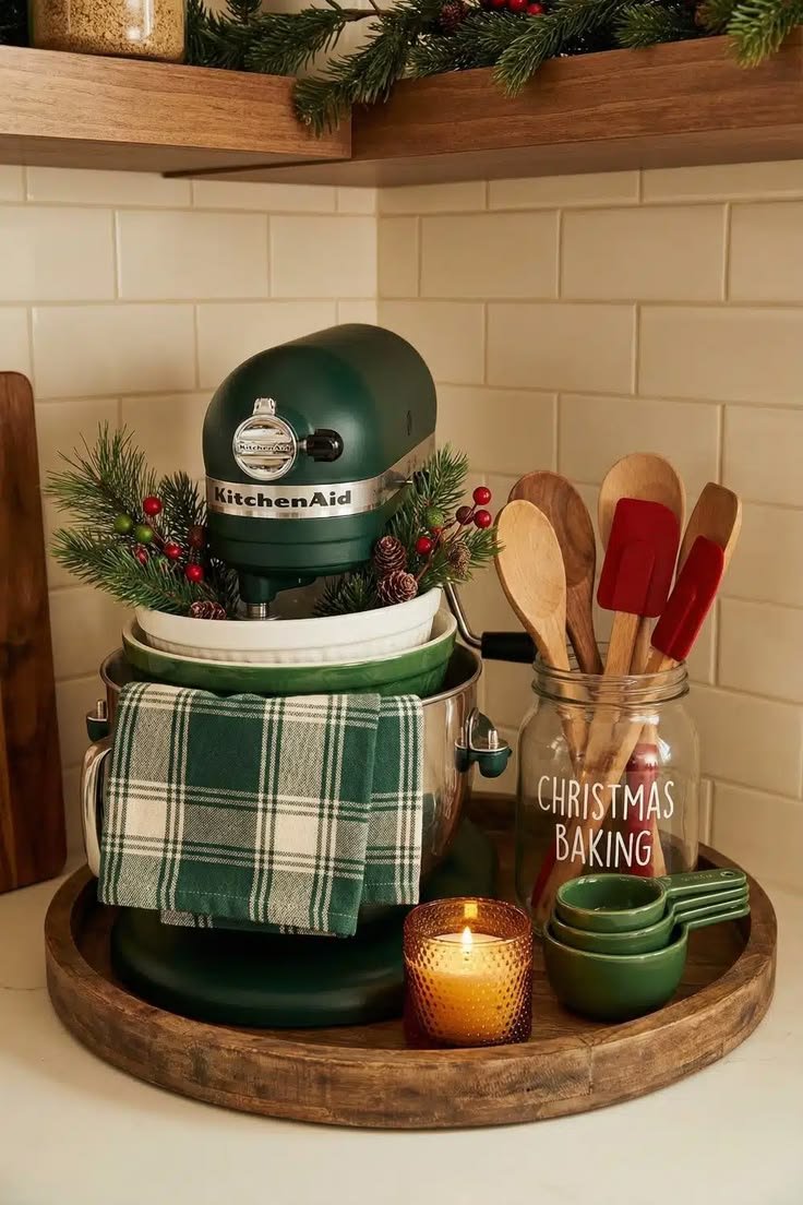 A green KitchenAid mixer styled with a plaid towel, greenery, and a baking utensil jar