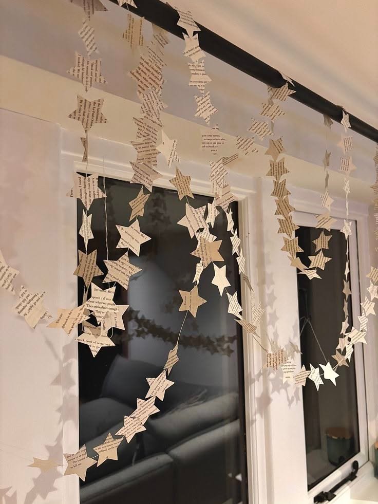 Garlands of paper stars cut from old book pages hanging in front of a window
