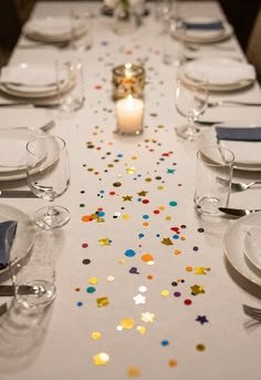 A white table runner scattered with colorful confetti between place settings