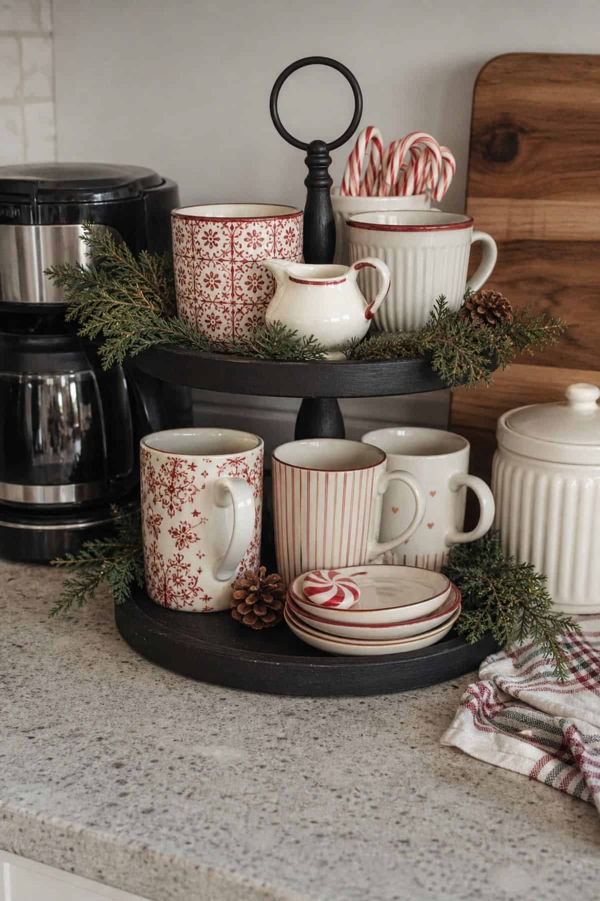 Black tiered tray with a red and white floral mug collection and cream pitcher