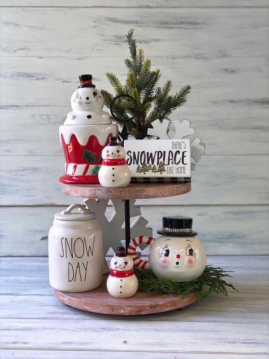 Tiered tray with a Theres Snowplace Like Home sign and Rae Dunn snowman canisters