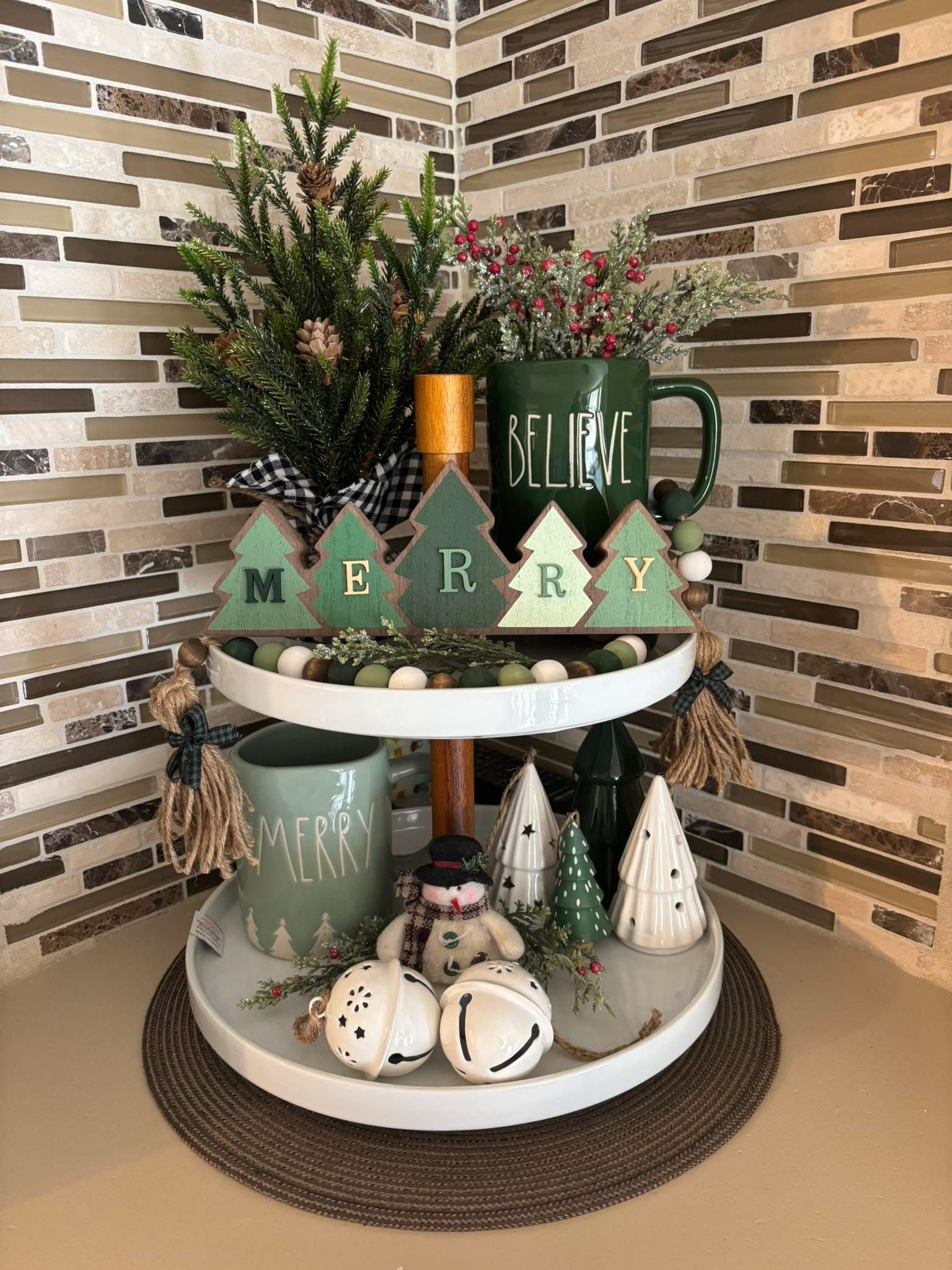 Tiered tray with wood tree letters spelling Merry and a green Believe mug