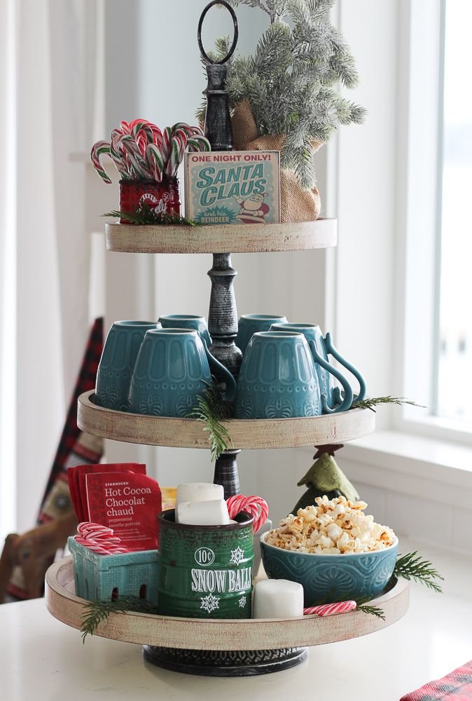 Vintage-style tiered tray with Santa Claus sign, teal mugs, and hot cocoa packets