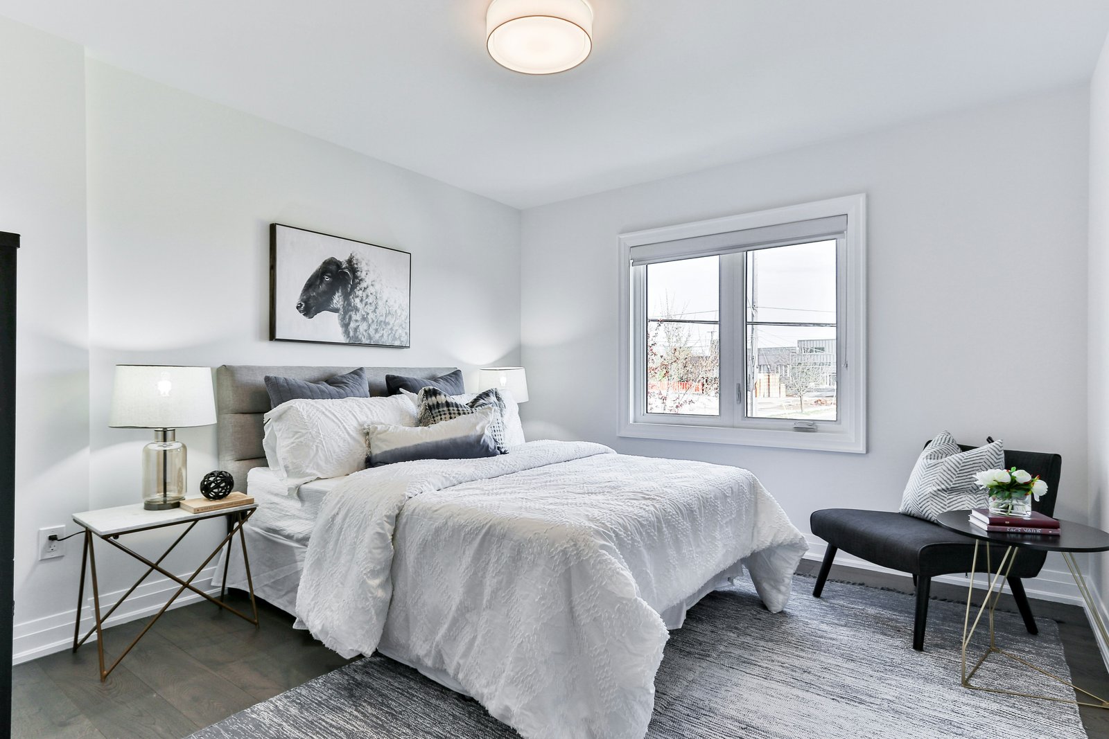 Bright neutral bedroom with textured white bedding and a brass side table